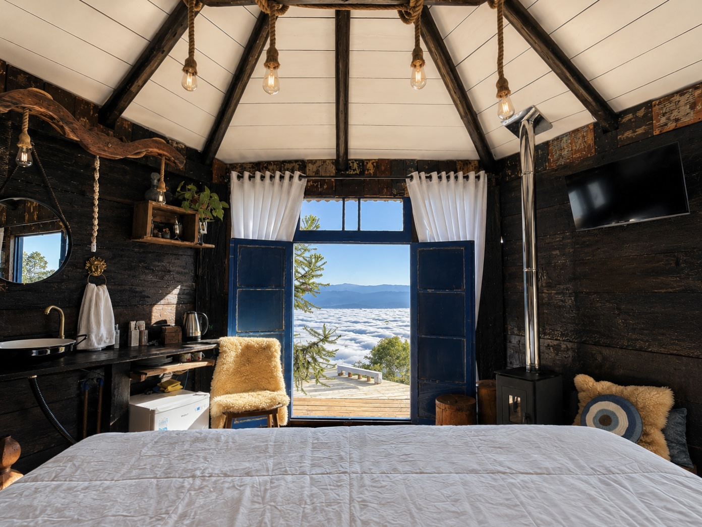 Quarto de madeira aconchegante com janelas abertas para as montanhas e o mar de nuvens